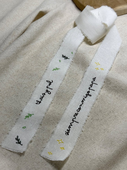 Cinta para ramo de novia personalizada en tela de lino crudo con diseño de bordado botánico de ramitas laterales y extremos deshilachados.
