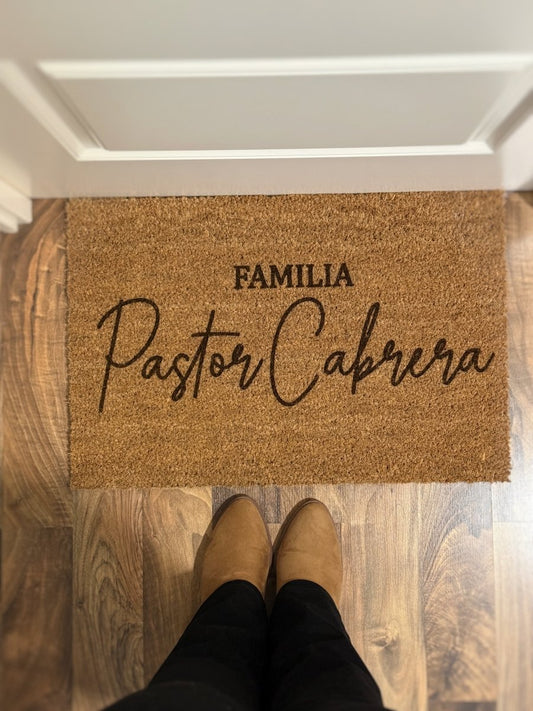 Entrada de casa con felpudo de coco natural y diseño familiar.
