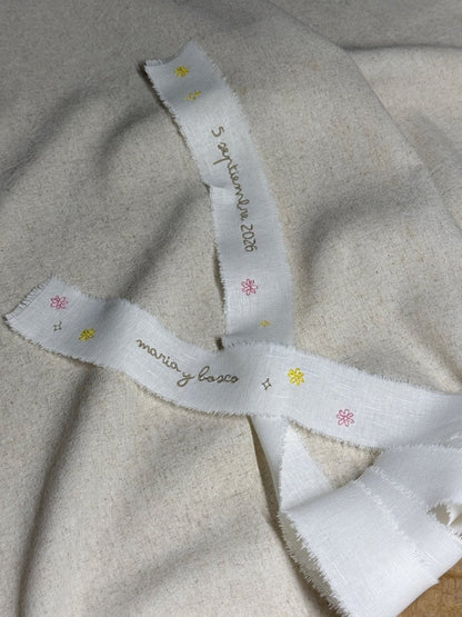 Lazo para ramo de novia personalizado en tela de lino con bordado de pequeñas estrellas y flores de colores salpicadas sobre el tejido natural.