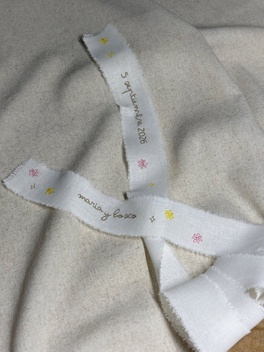 Lazo para ramo de novia personalizado en tela de lino con bordado de pequeñas estrellas y flores de colores salpicadas sobre el tejido natural.