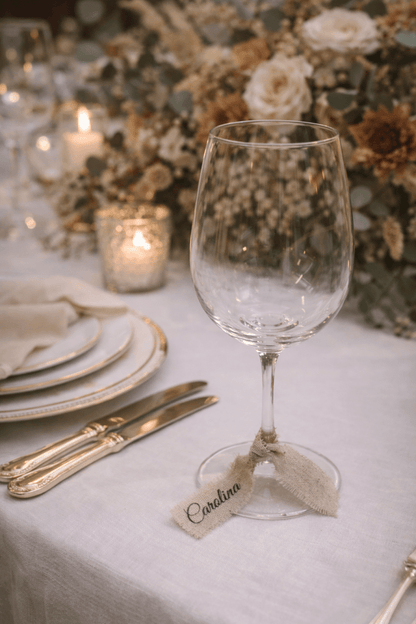 Decoración de mesa de boda con marcasitios de lino personalizados atados a la cristalería.